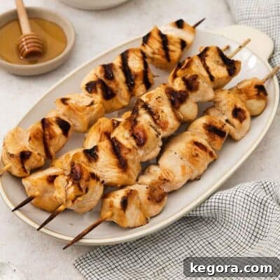 A side view of honey sesame chicken skewers on a platter, ready to be served.