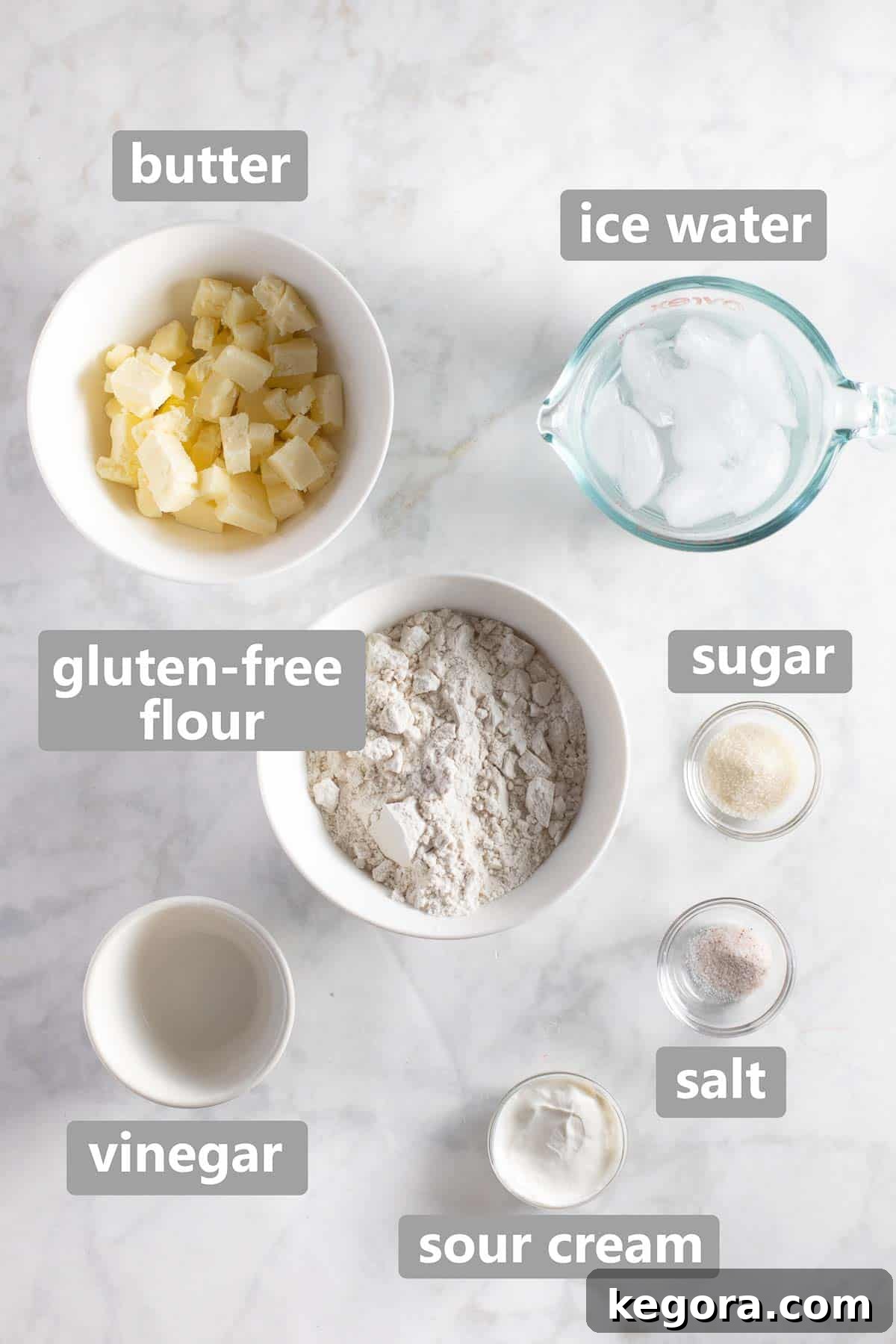 Overhead shot of gluten-free pie crust ingredients laid out, including flour, butter, and liquid components.