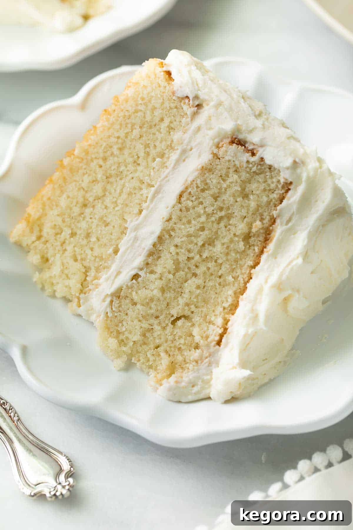 The Ultimate Gluten Free Vanilla Cake 3 A perfectly baked slice of gluten-free vanilla cake on a white plate, showcasing its incredibly soft and moist crumb.