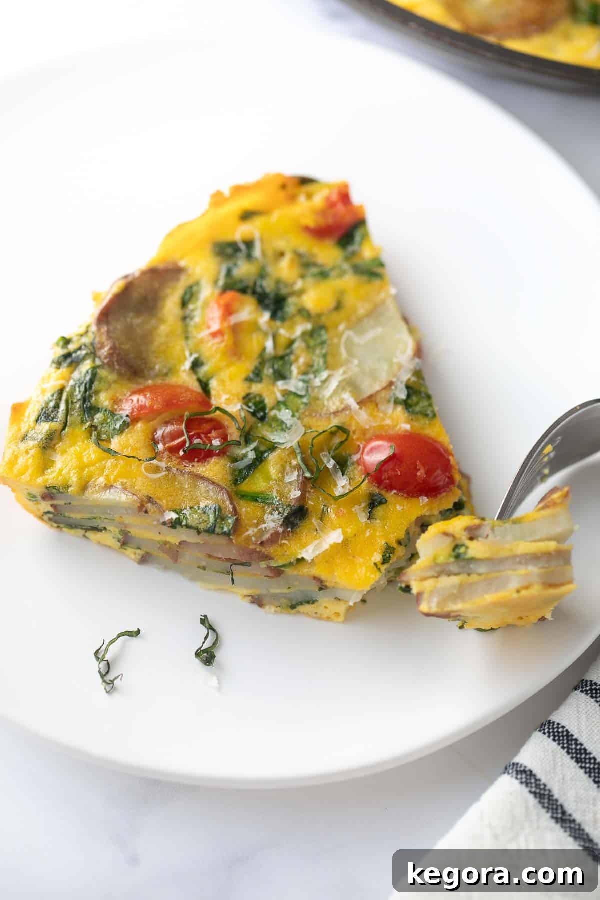 Hearty Vegetable Frittata Slice A perfectly plated slice of golden-brown vegetable frittata, revealing layers of potatoes, spinach, and other colorful vegetables, ready to be eaten.