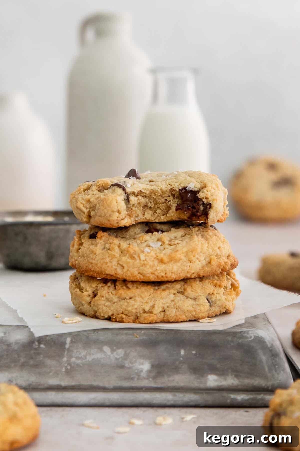 A perfectly balanced stack of three homemade almond flour oatmeal cookies with chocolate chips, one cookie with a delightful bite taken out, showcasing its soft and chewy interior texture.