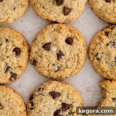 Close-up photograph of a stack of chocolate chip almond flour oatmeal cookies, with one cookie showing a bite taken out, emphasizing its soft and chewy texture.