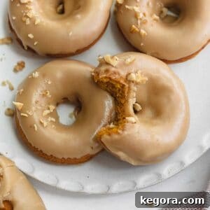 Gluten-free pumpkin donuts on white plate topped with walnuts