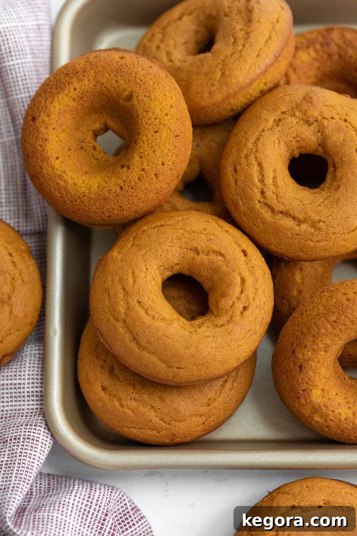 Baked pumpkin donuts cooling on a baking sheet before being glazed, ready for their delicious topping.