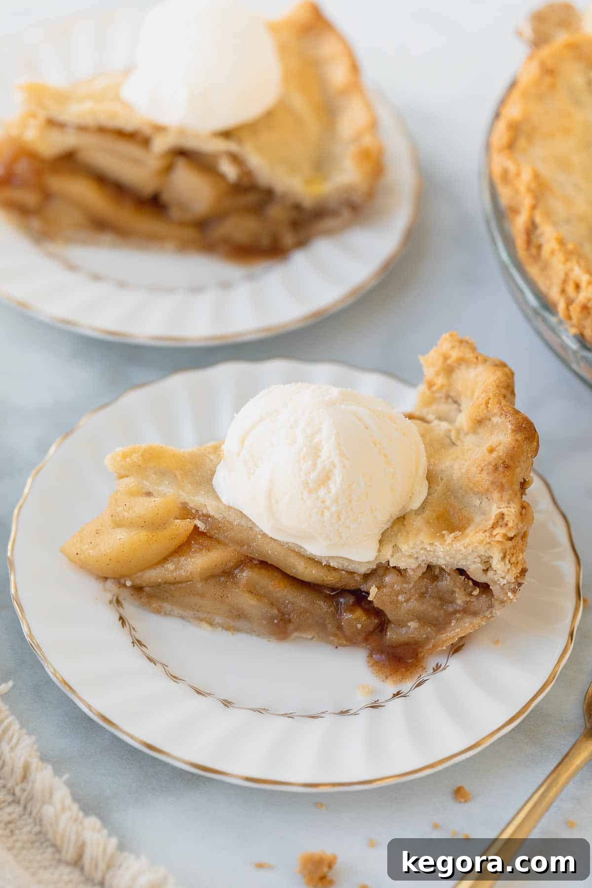A slice of gluten-free apple pie on a white plate, topped with vanilla ice cream.
