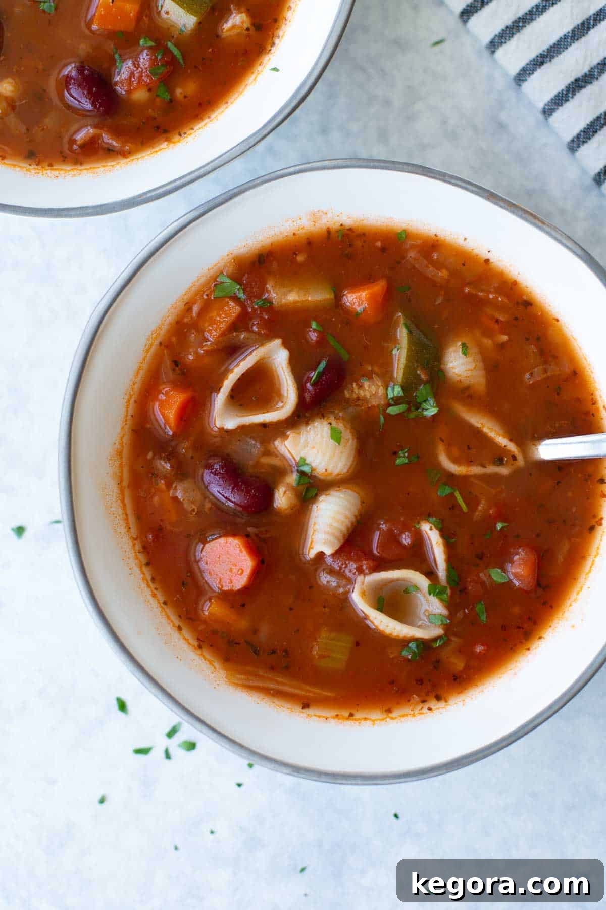 Hearty Gluten-Free Minestrone 3 Close-up of a bowl of gluten-free minestrone soup with spoon and garnish