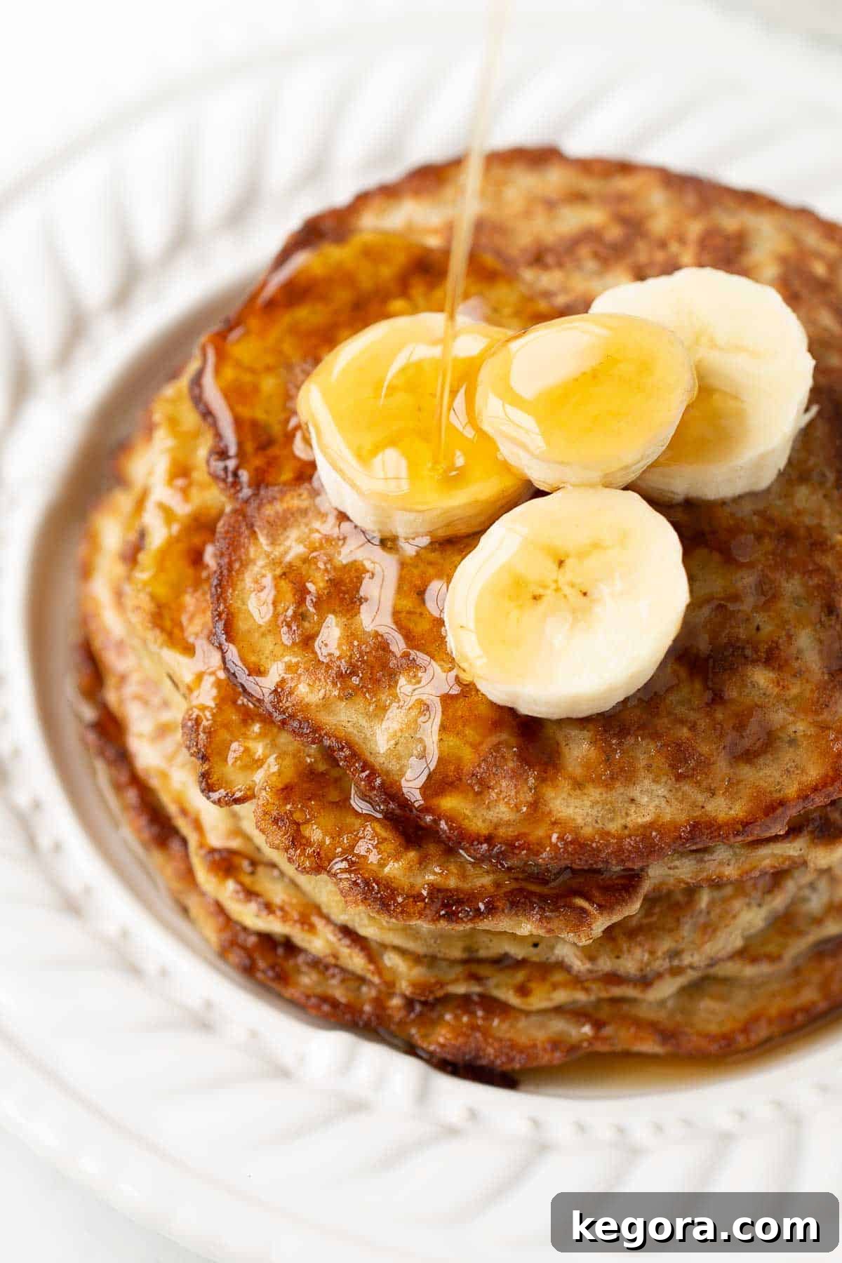 Close-up shot of freshly cooked banana oat pancakes stacked on a plate, garnished with fresh fruit.