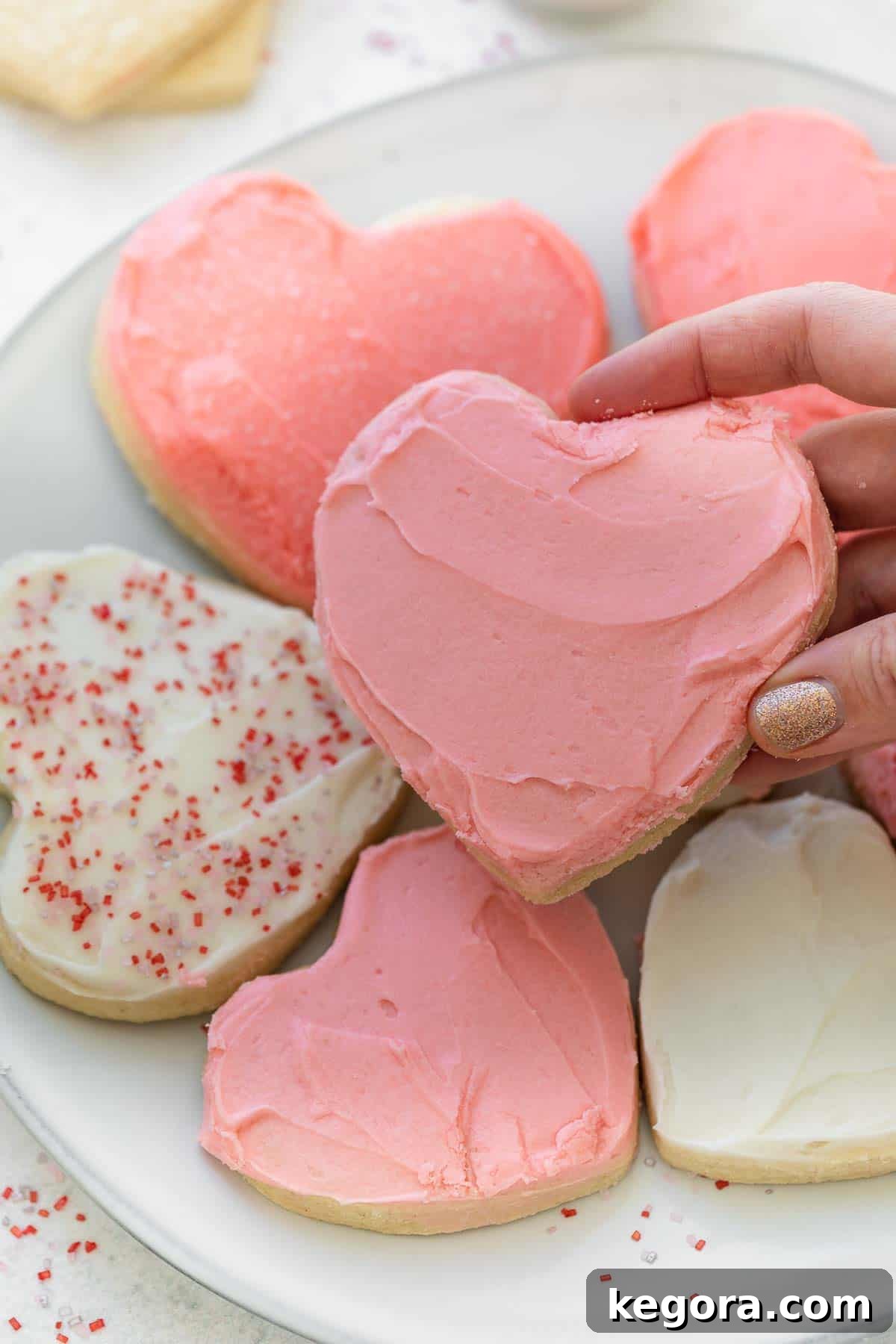 Perfect Gluten-Free Sugar Cookies 9 close up of gluten free heart cookie being held with hand over plate of other cookies