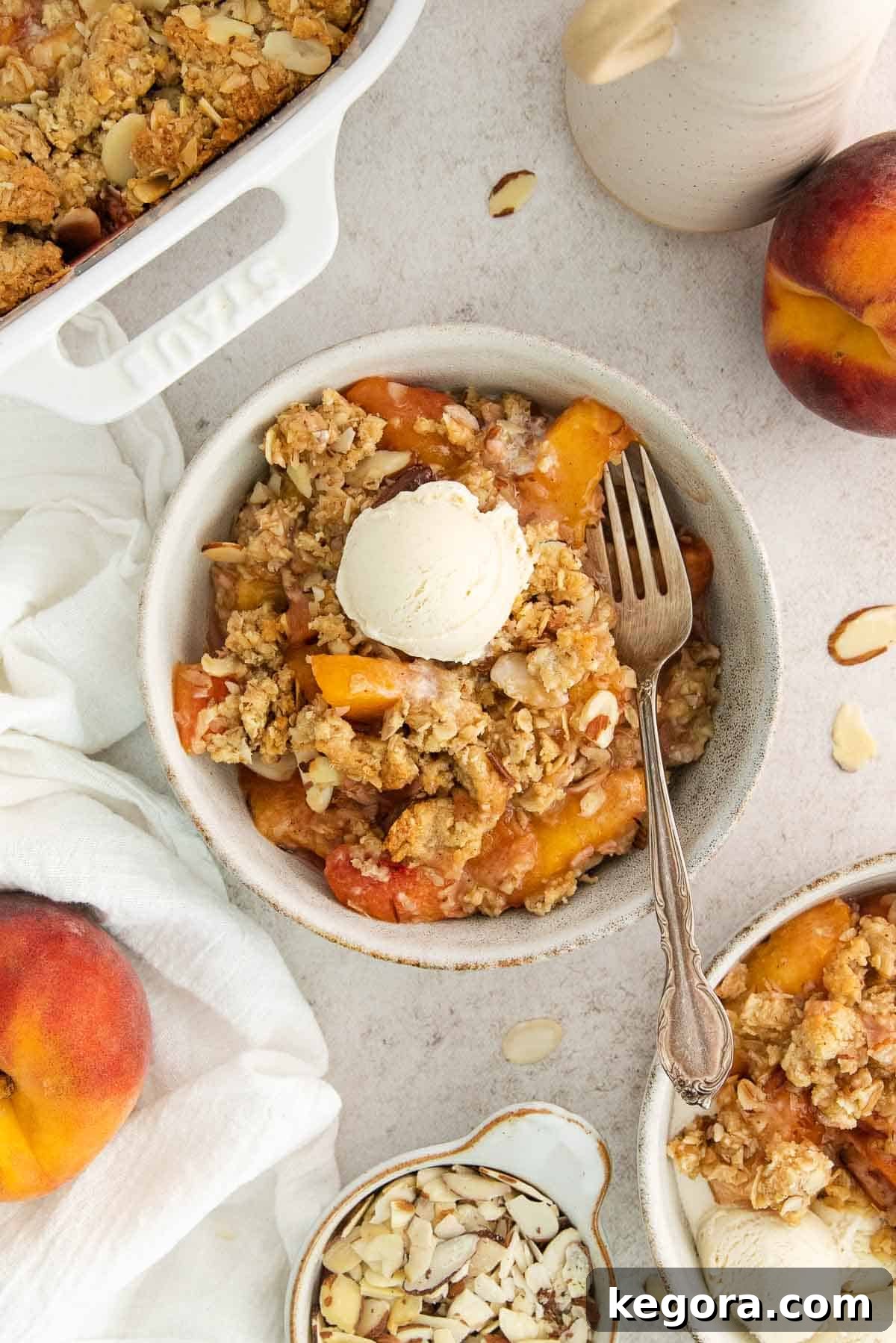 A delectable bowl of gluten-free peach crisp, topped with a scoop of vanilla ice cream, with a fork poised to dig in.