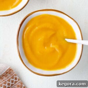 Overhead shot of creamy butternut squash soup in a bowl with a spoon, ready to eat.