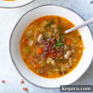 Overhead shot of a rustic white bean soup in a white and gray bowl, inviting and warm.