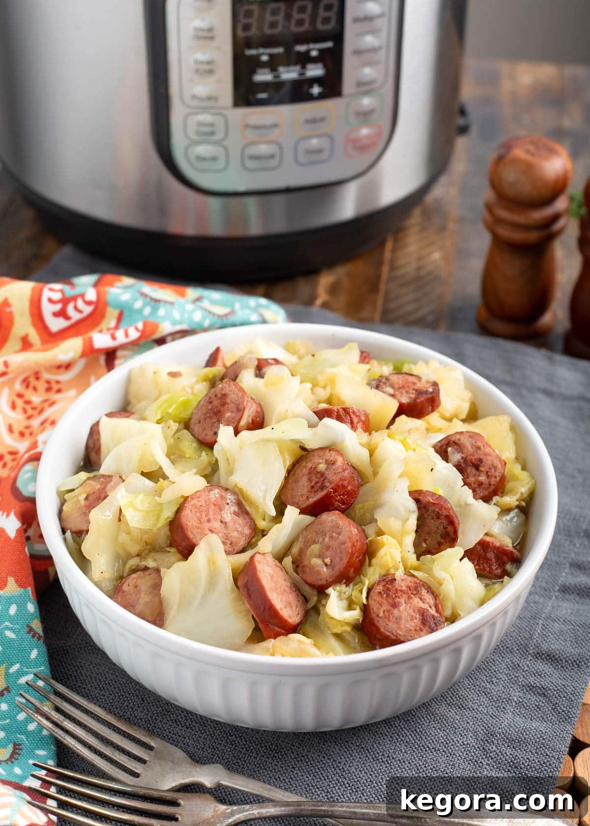 A serving of Instant Pot Cabbage and Kielbasa in a white ceramic bowl, garnished with fresh parsley.