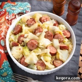 A dish of Instant Pot Cabbage and Kielbasa in a white bowl, garnished.
