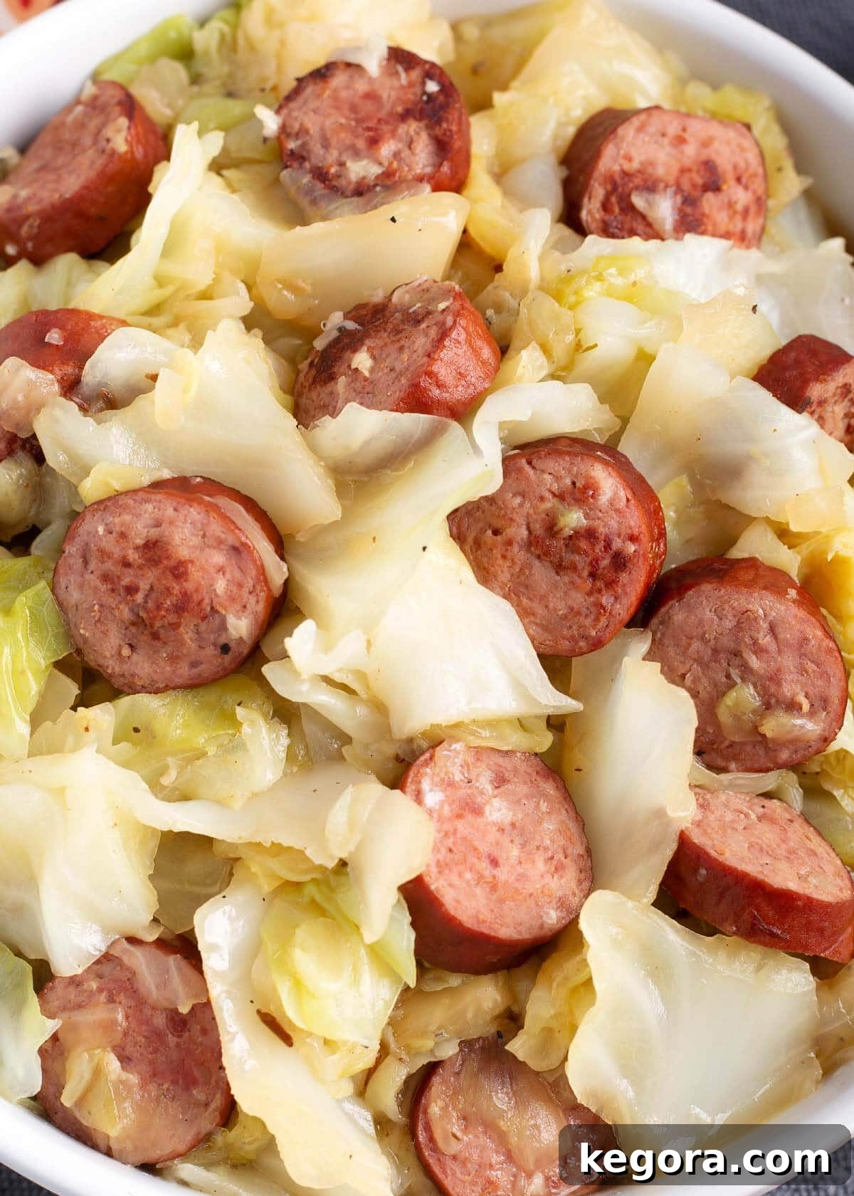 Close-up shot of cooked kielbasa sausage slices mixed with tender cabbage and onions, showcasing the dish's texture.