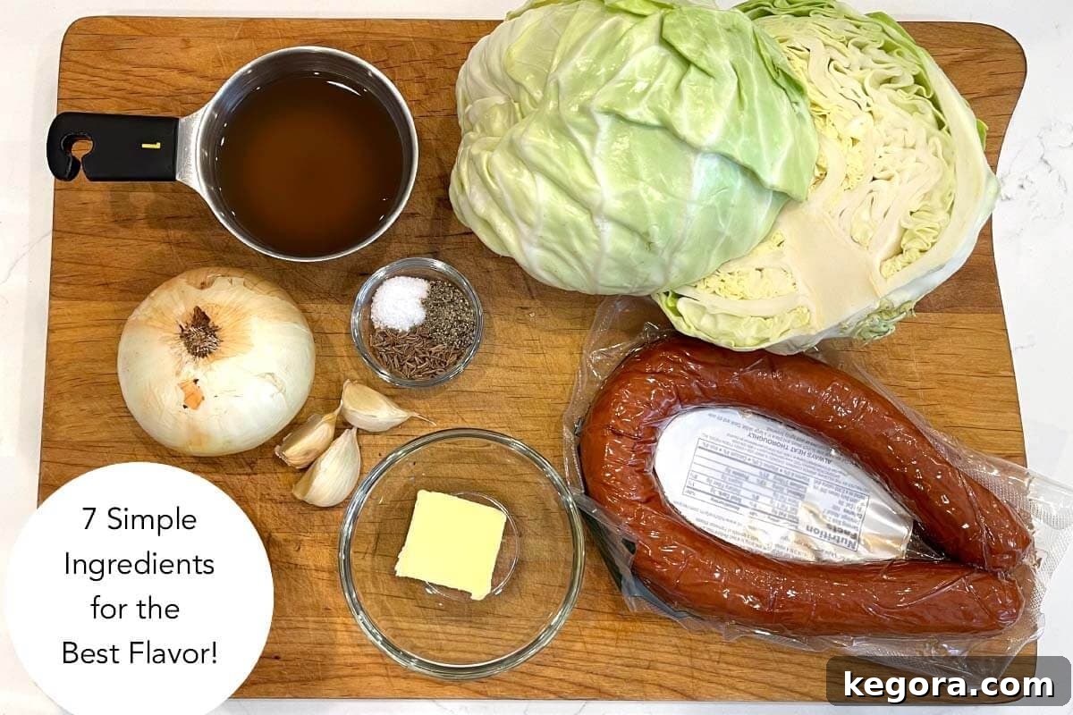 All ingredients for Instant Pot Cabbage and Kielbasa laid out on a kitchen counter: butter, kielbasa, cabbage, onion, garlic, caraway seeds, salt, pepper, and vegetable broth.