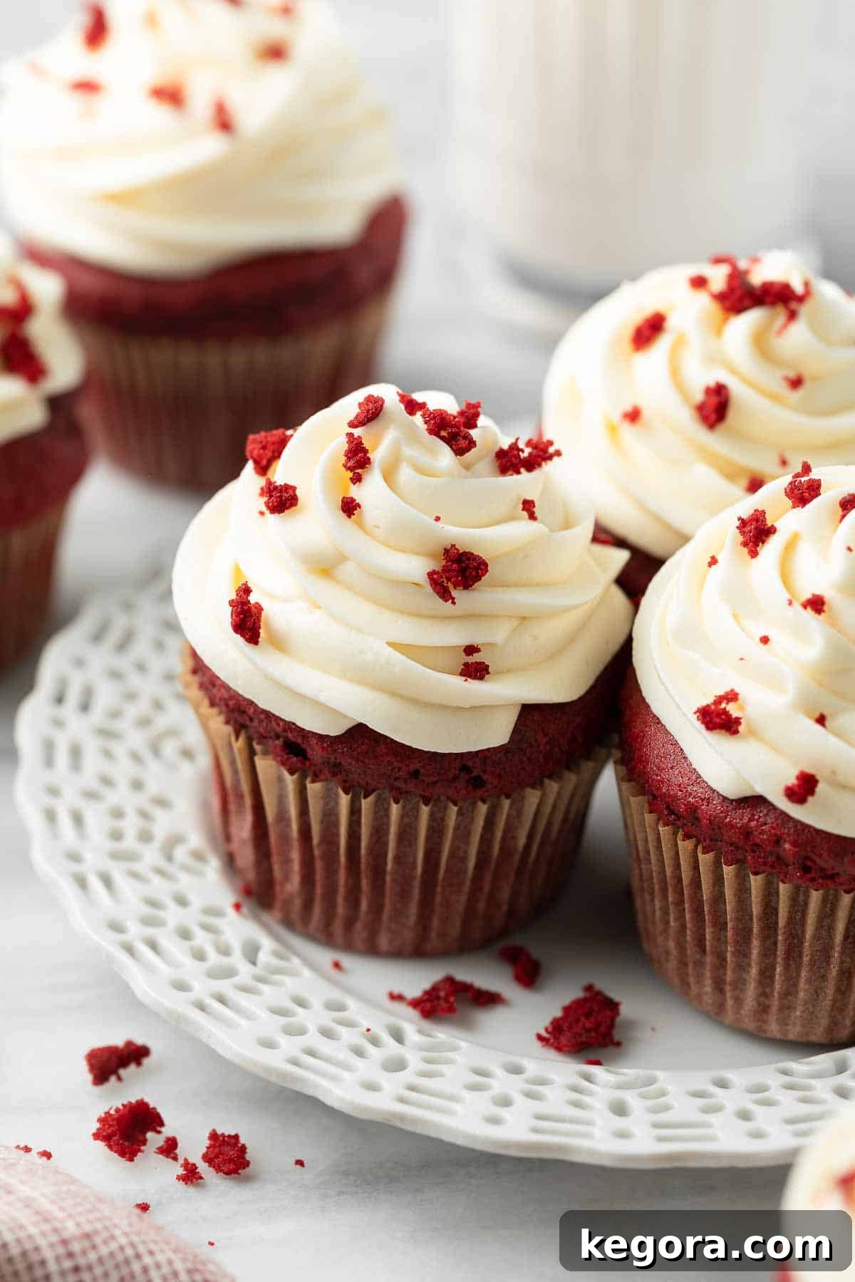 Plate of perfectly baked gluten-free red velvet cupcakes topped with cream cheese frosting and cake crumbs.