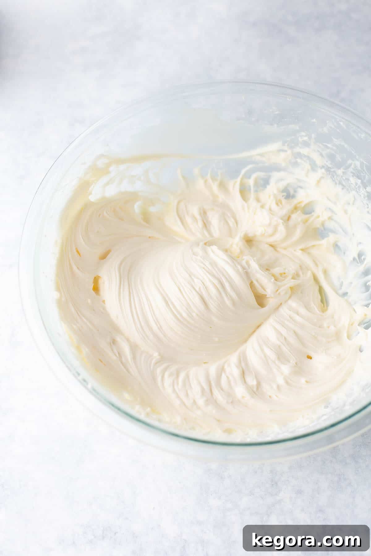 Glass bowl filled with creamy, homemade cream cheese frosting, ready for piping.