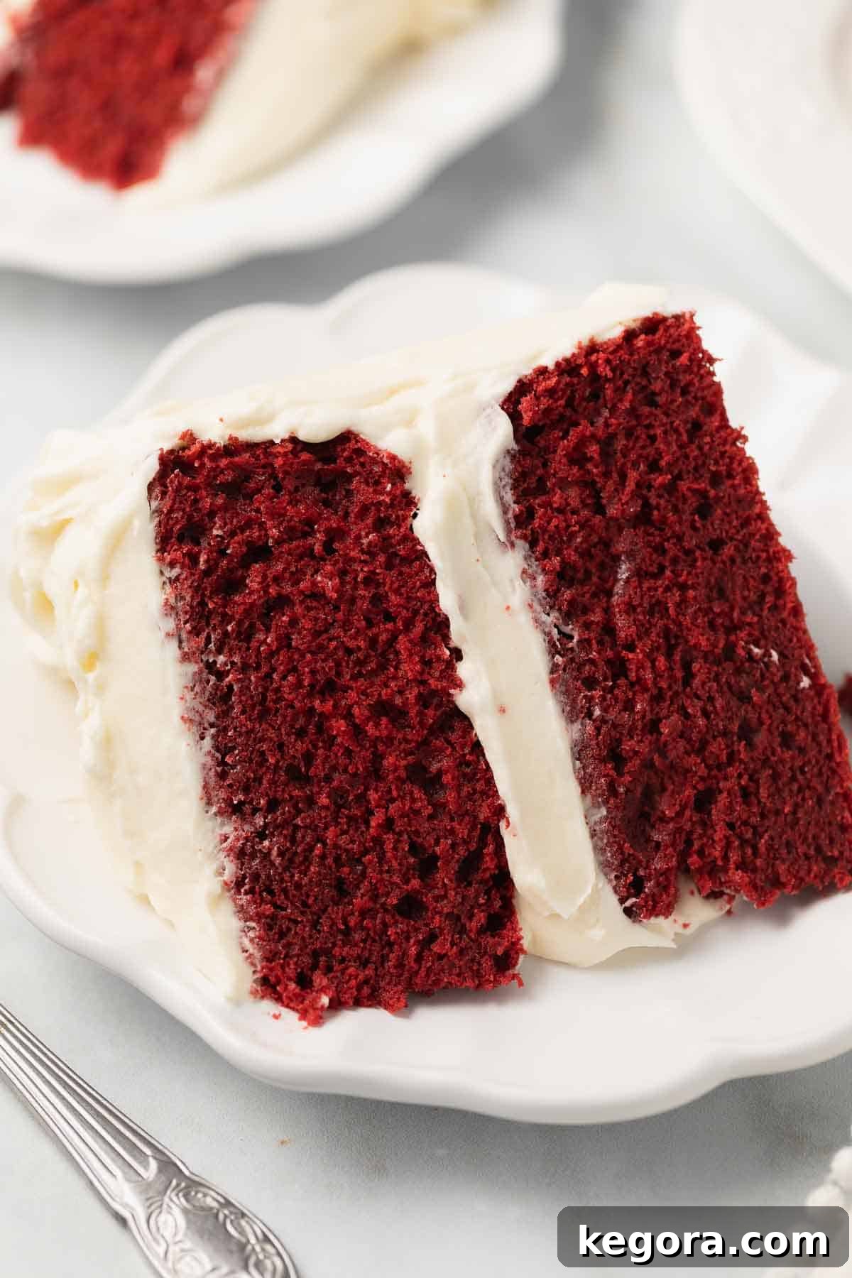 A stunning gluten-free red velvet cake, perfectly sliced on a white plate with a fork, ready to be enjoyed.