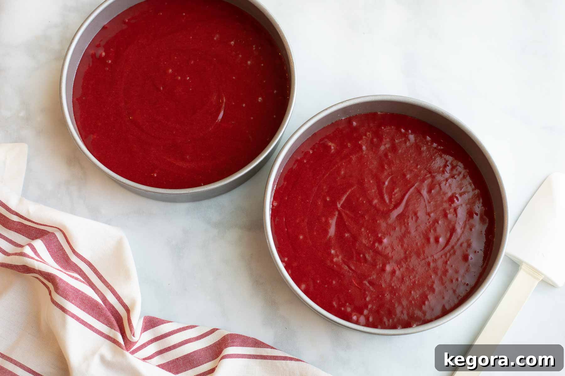 Vibrant red velvet cake batter poured into baking pans, ready for the oven.