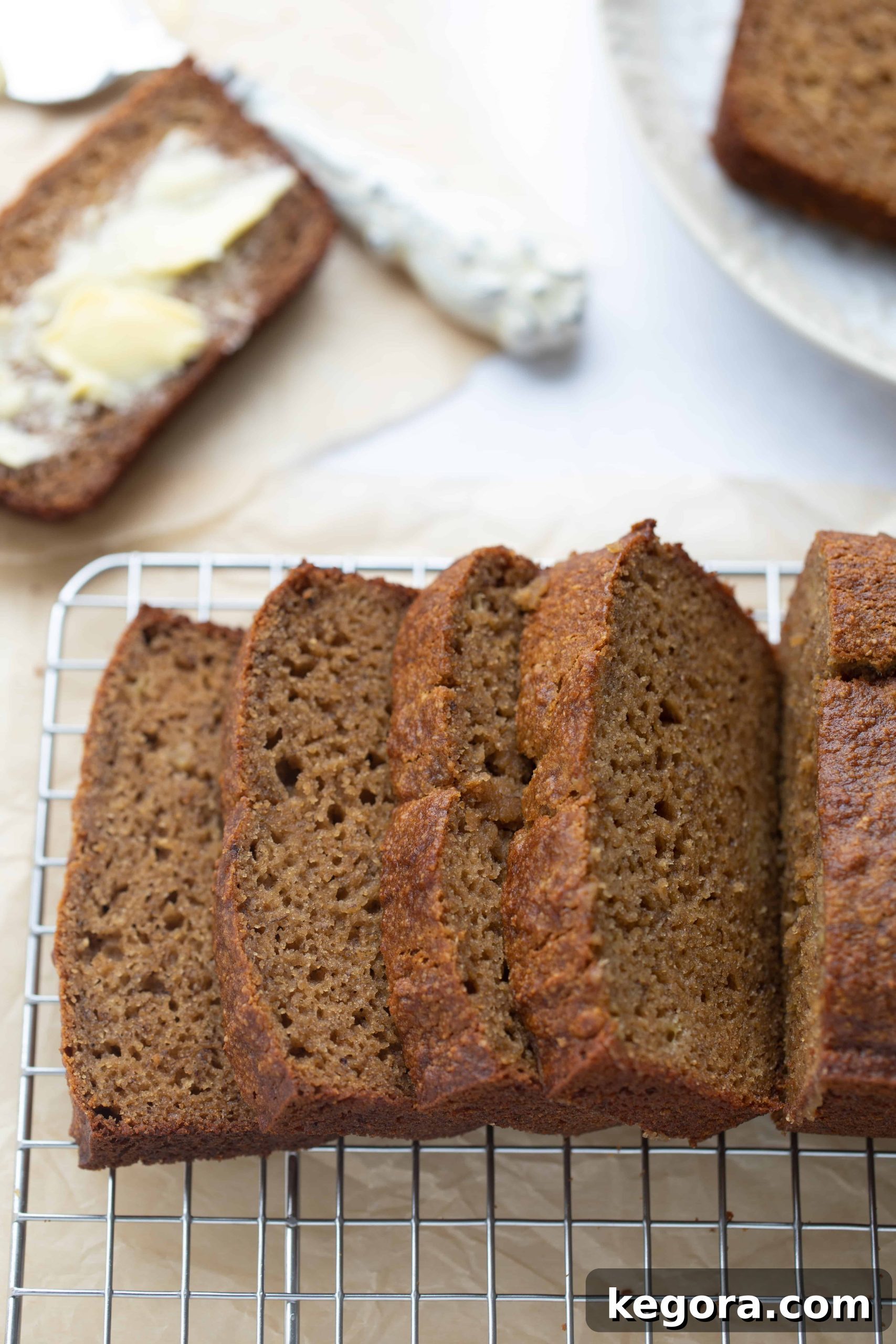Slices of moist paleo banana bread on a wire cooling rack, showcasing its tender crumb and golden-brown crust.