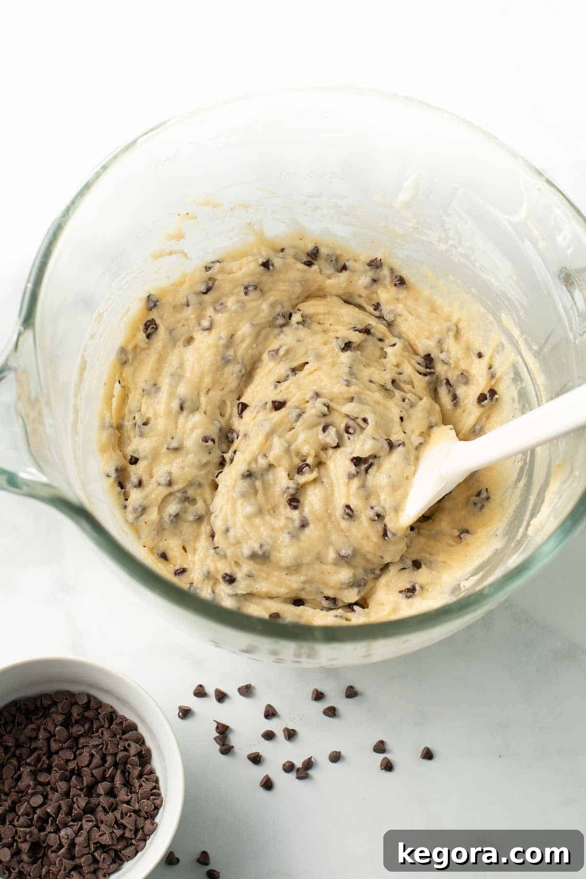 Decadent Gluten-Free Chocolate Chip Muffins 6 A mixing bowl filled with smooth gluten-free chocolate chip muffin batter, with a spatula resting in it, ready for the final step of adding chocolate chips.
