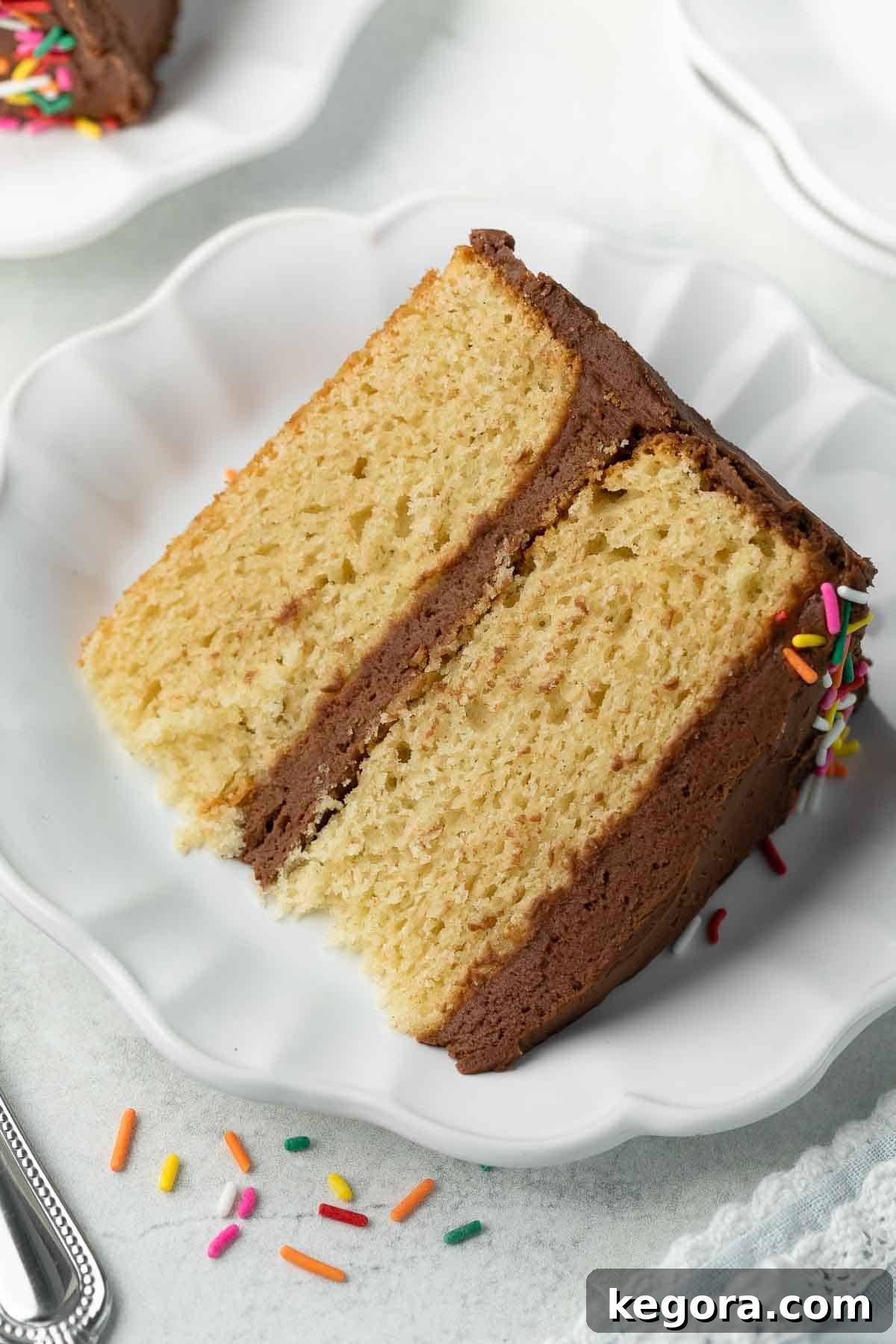 Ultimate Gluten-Free Birthday Cake 2 A beautifully sliced gluten-free birthday cake on a white plate, revealing its moist and fluffy texture.