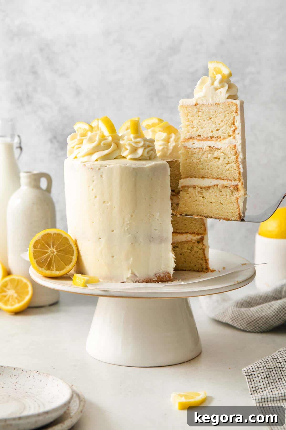 A slice of lemon cake being taken out of the cake on a cake stand