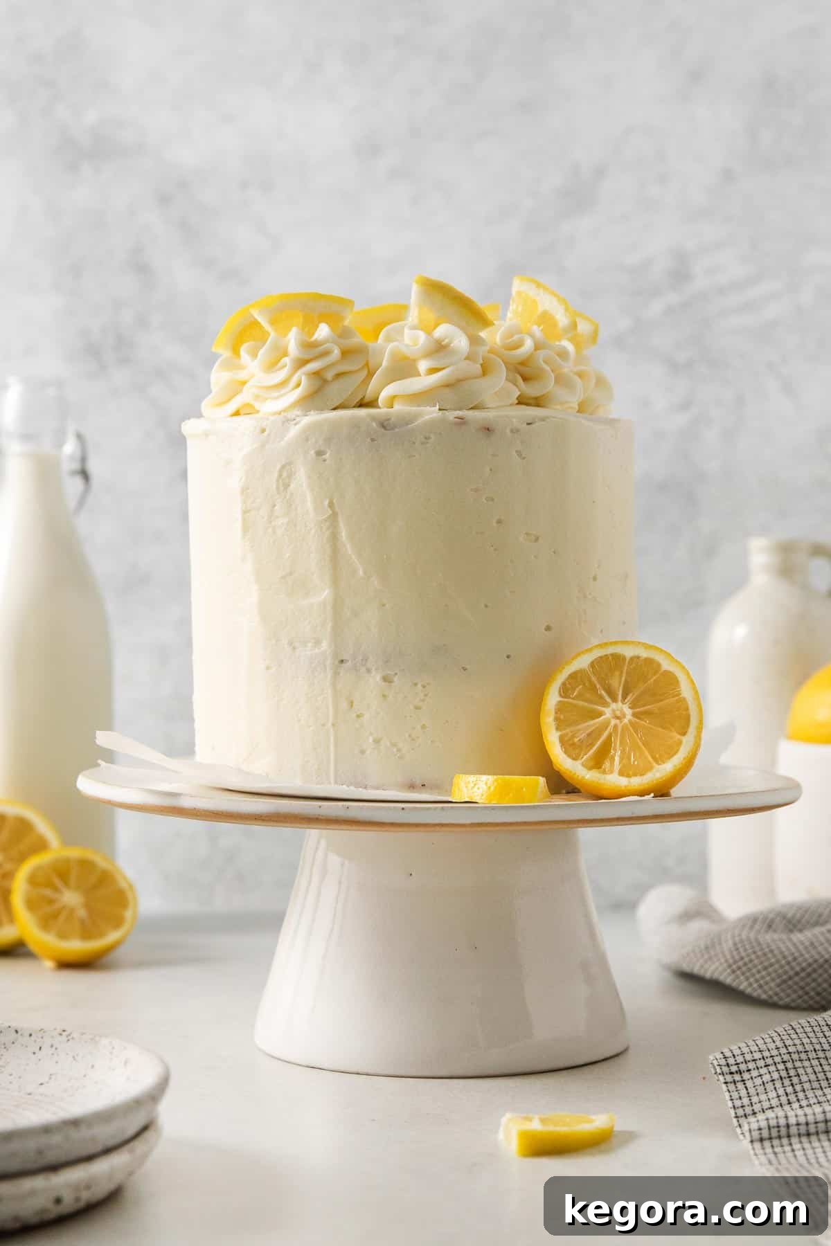 Gluten-free lemon cake on a cake stand with lemons on top and on the side