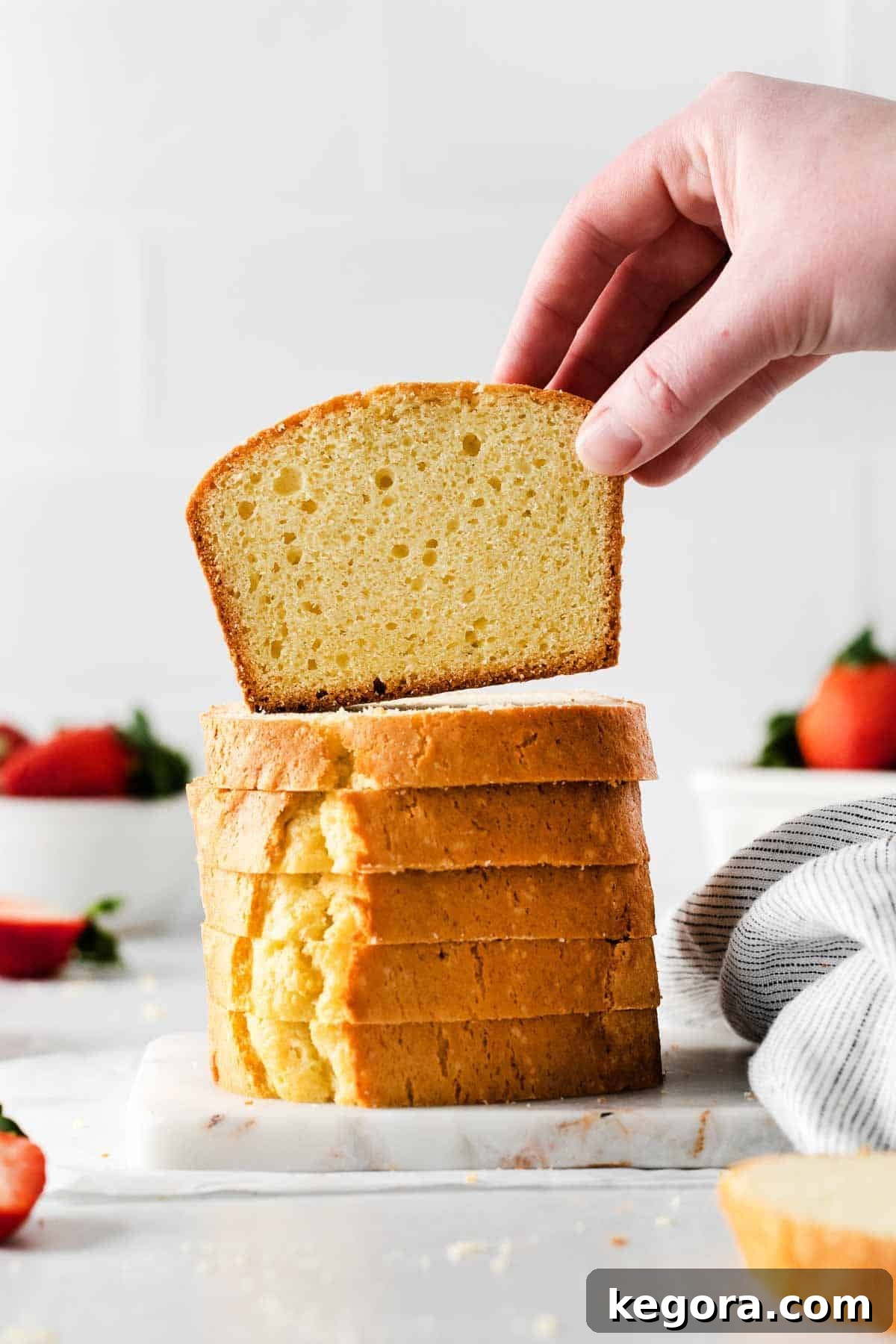 Seriously Delicious Gluten-Free Pound Cake 7 Stacked slices of gluten-free pound cake, with a hand reaching for a piece, illustrating its inviting texture.