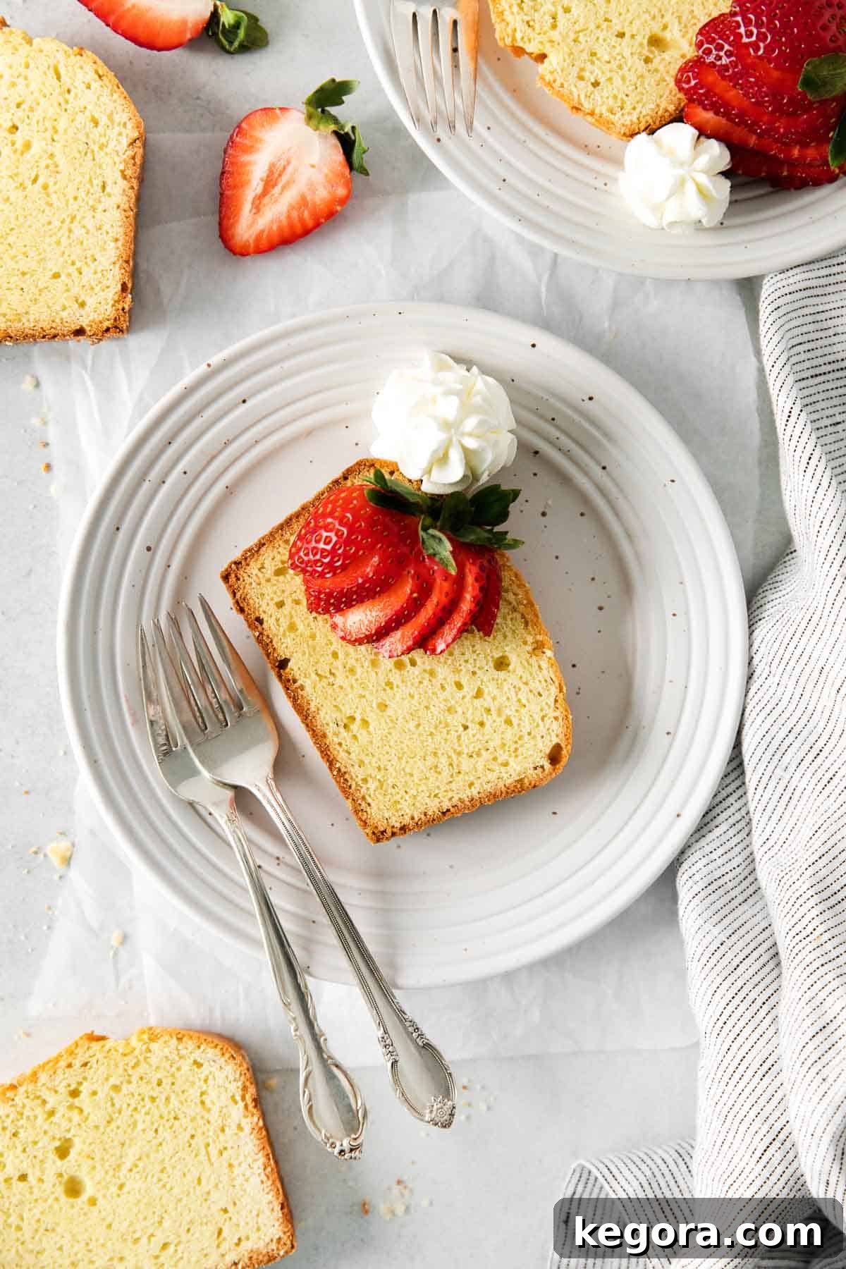 Seriously Delicious Gluten-Free Pound Cake 8 A beautiful slice of gluten-free pound cake served on a white plate, elegantly topped with fresh strawberries and a dollop of cream.