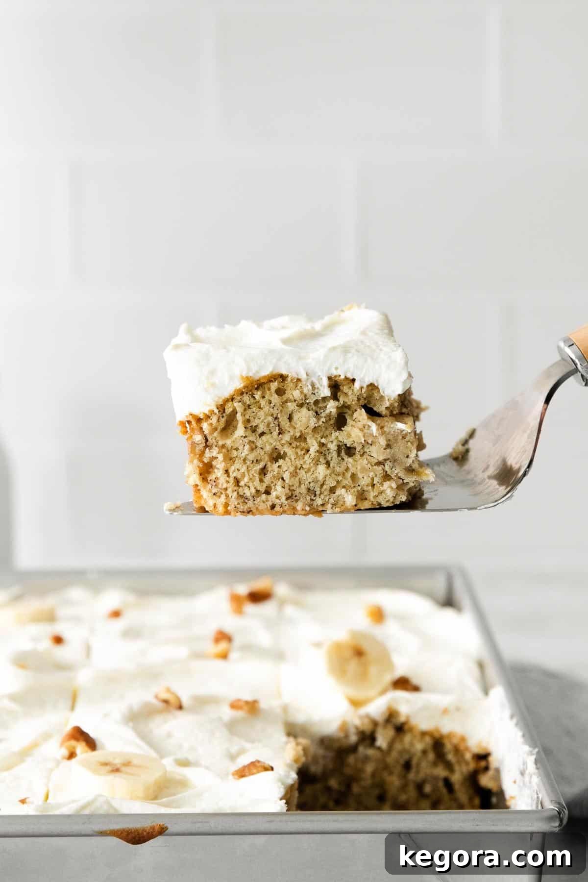 Golden Gluten-Free Banana Treat 7 A perfectly baked slice of gluten-free banana cake being lifted from the pan with a serving spoon, showing its moist texture and golden crust.