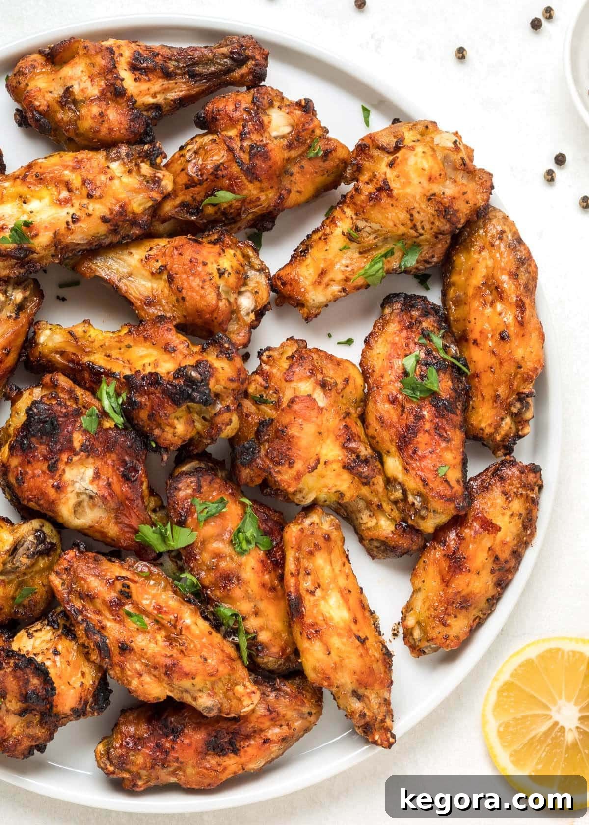 Air Fryer Lemon Pepper Chicken Wings on a plate, garnished with fresh lemon slices and parsley.