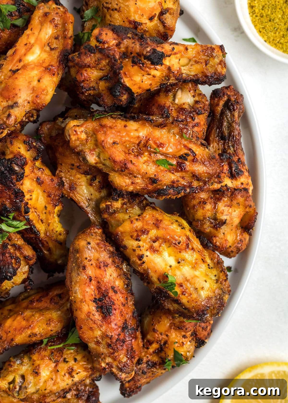A serving of Air Fryer Lemon Pepper Chicken Wings on a modern white plate, showcasing a mix of flats and drumettes.