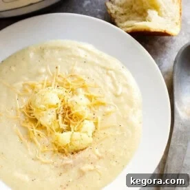 Smoky Creamy Cauliflower Soup in a white bowl next to spoon and roll