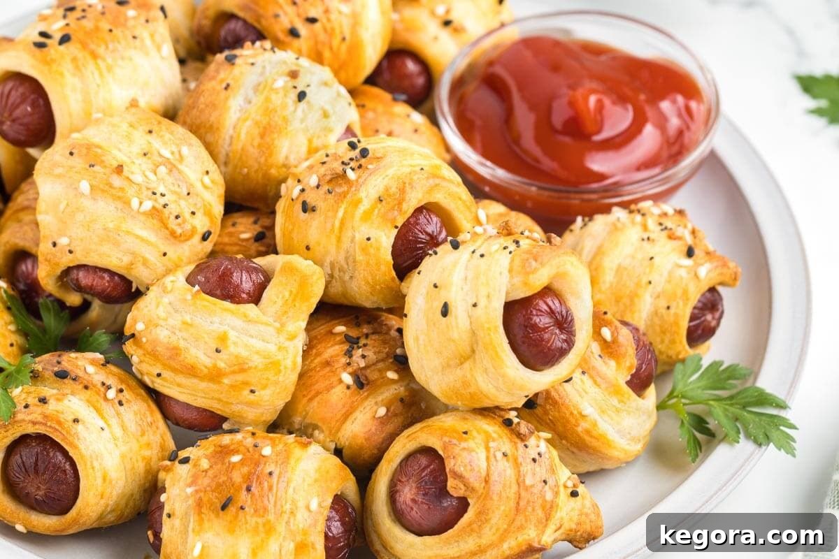 A plate piled high with crispy Air Fryer Pigs in a Blanket, garnished and ready for serving.