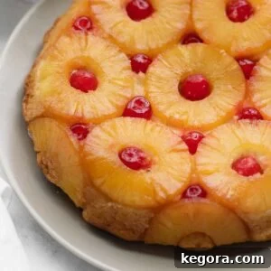 A beautiful slice of golden gluten-free pineapple upside-down cake, revealing its caramelized pineapple and cherry topping, elegantly plated and ready to serve.