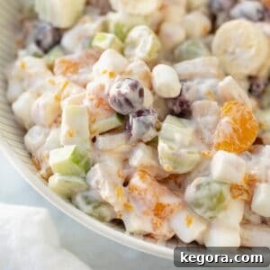 A vibrant close-up shot of a holiday fruit salad in a pristine white serving bowl, brimming with a colorful assortment of fresh, juicy fruits, ready to be enjoyed.