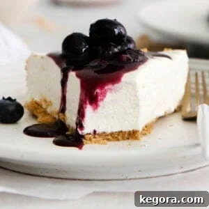 A pristine slice of gluten-free no-bake cheesecake on a plate, elegantly topped with fresh, plump blueberries, highlighting its creamy texture and fresh appeal.