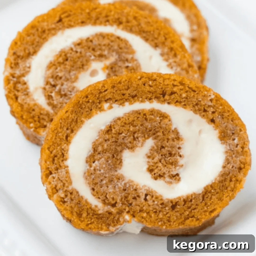 A beautifully sliced gluten-free pumpkin roll with a creamy filling, artfully arranged on a plate.