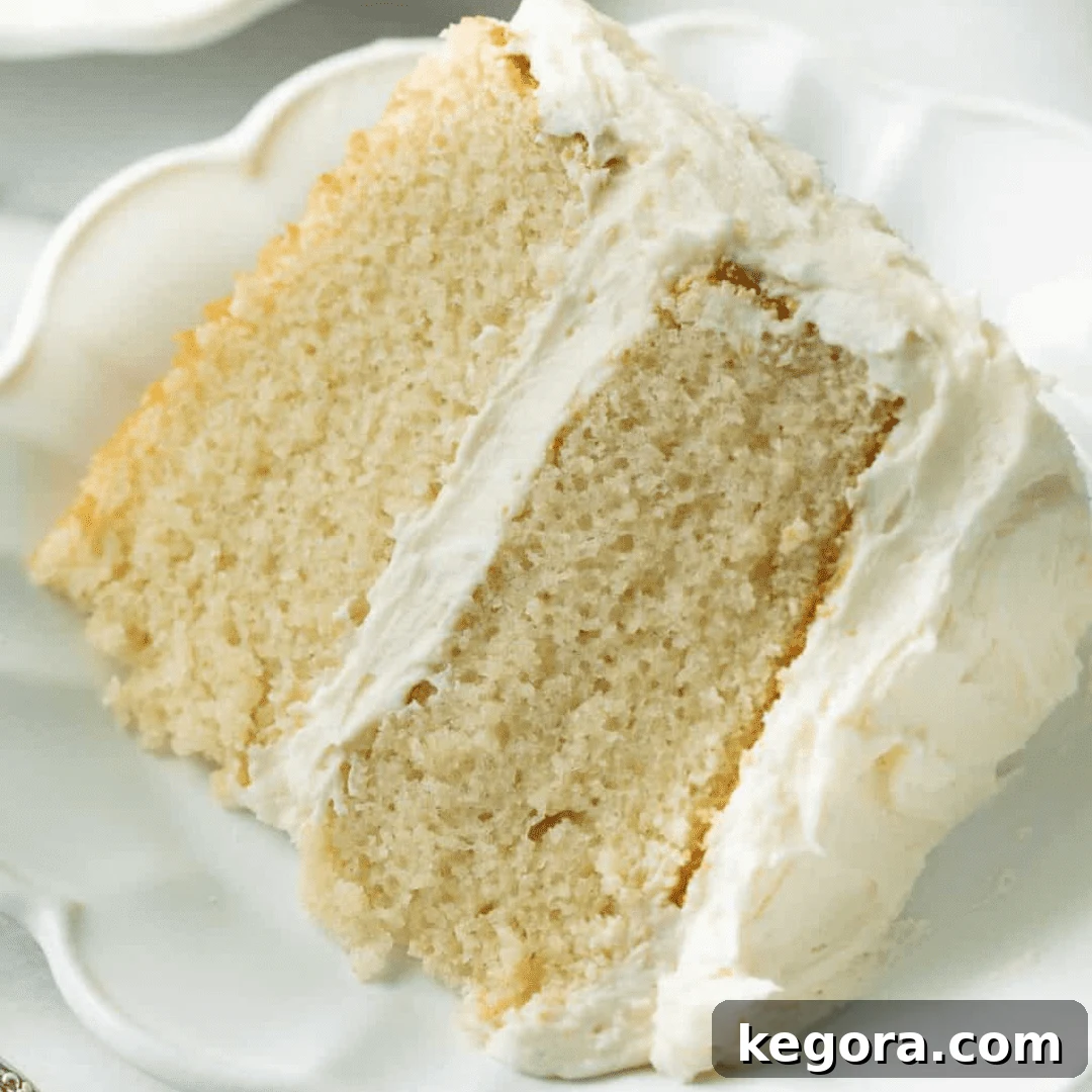 A perfectly sliced piece of the best gluten-free vanilla cake on a white plate, showcasing its soft, pillowy crumb.
