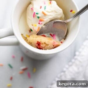 A mug cake with a spoon on a countertop