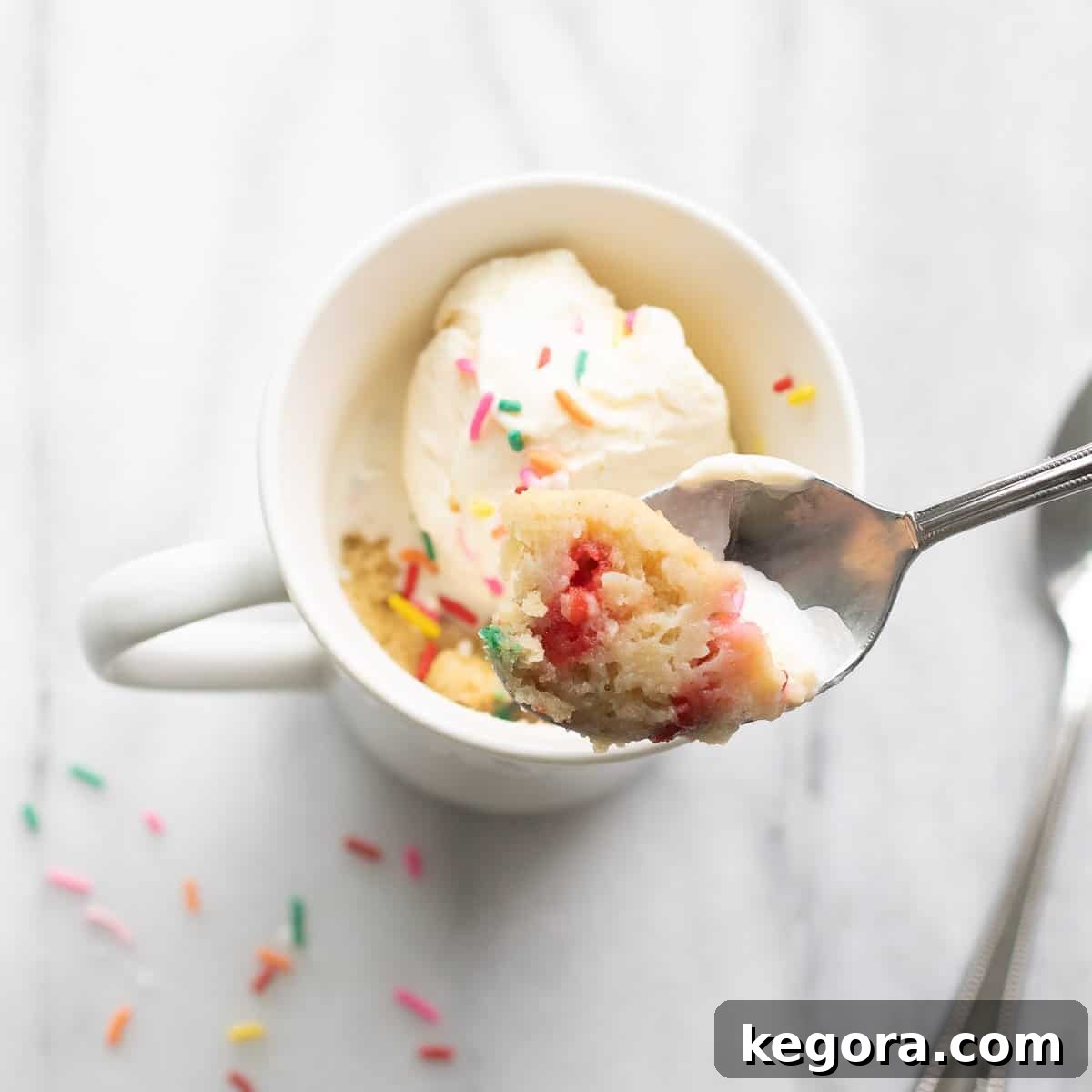 A gluten-free mug cake with a spoon scooping into the warm, moist cake.