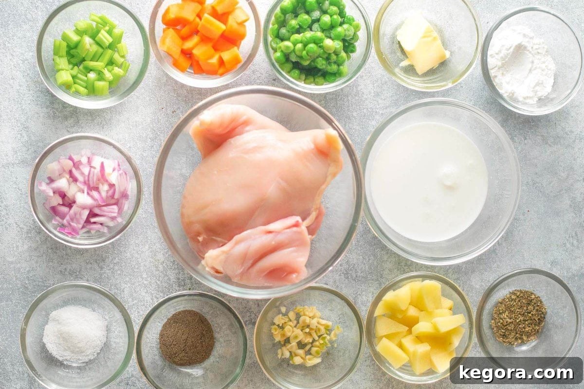 Instant Pot Chicken Pot Pie Soup ingredients laid out on a white surface, including chicken, vegetables, broth, and seasonings.