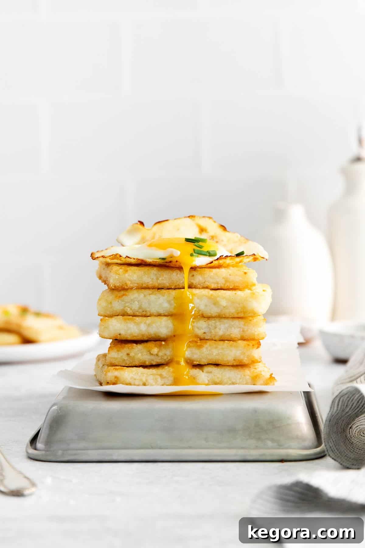 Golden Grit Fritters 7 A beautiful stack of crispy grit cakes, perfectly golden, topped with a runny fried egg on a rustic pan.