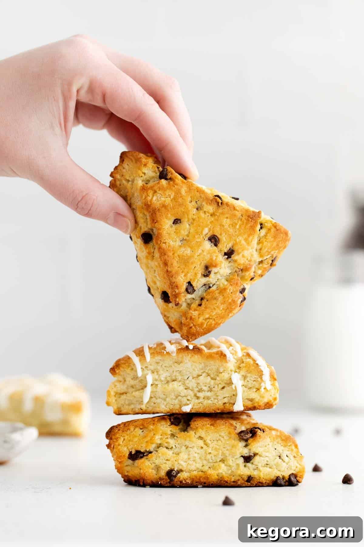 Stacked gluten-free chocolate chip scones on a plate, with a hand reaching for one