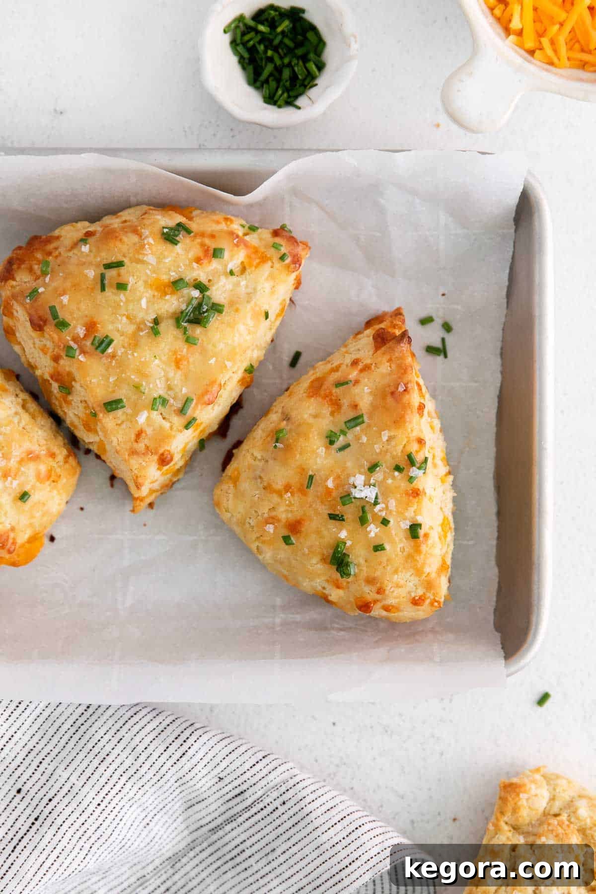 Fluffy Gluten-Free Cheese Scones 3 Freshly baked gluten-free cheese scones arranged on a baking tray lined with parchment paper, golden brown and inviting.