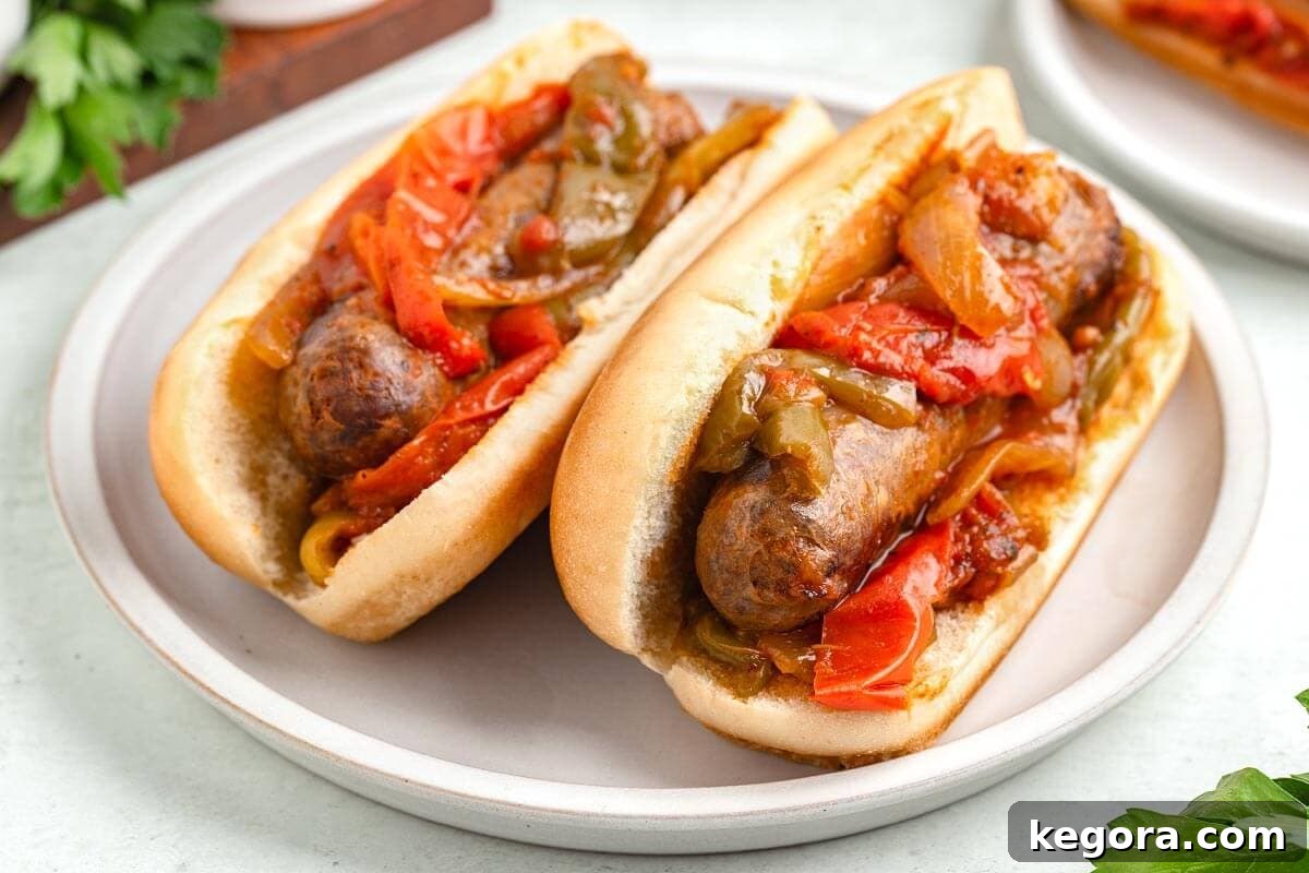 Set It and Forget It Sausage and Peppers 3 Two hearty sausage and pepper hoagies served in buns on a white plate, ready to be enjoyed.