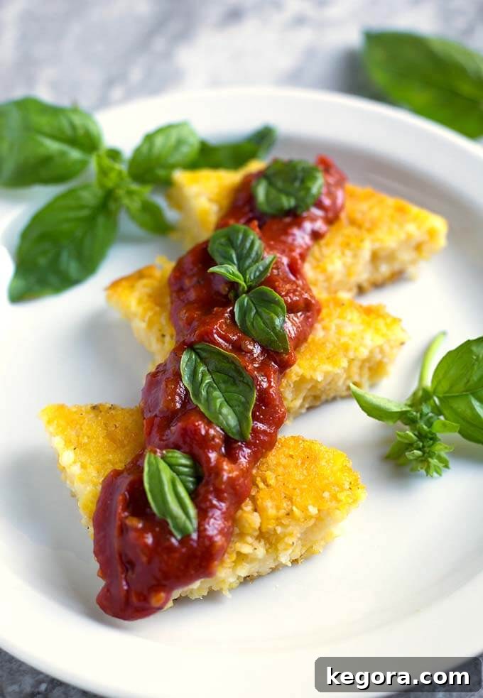 No-Stir Instant Pot Polenta 3 Polenta slices on a white plate with red sauce and basil leaves