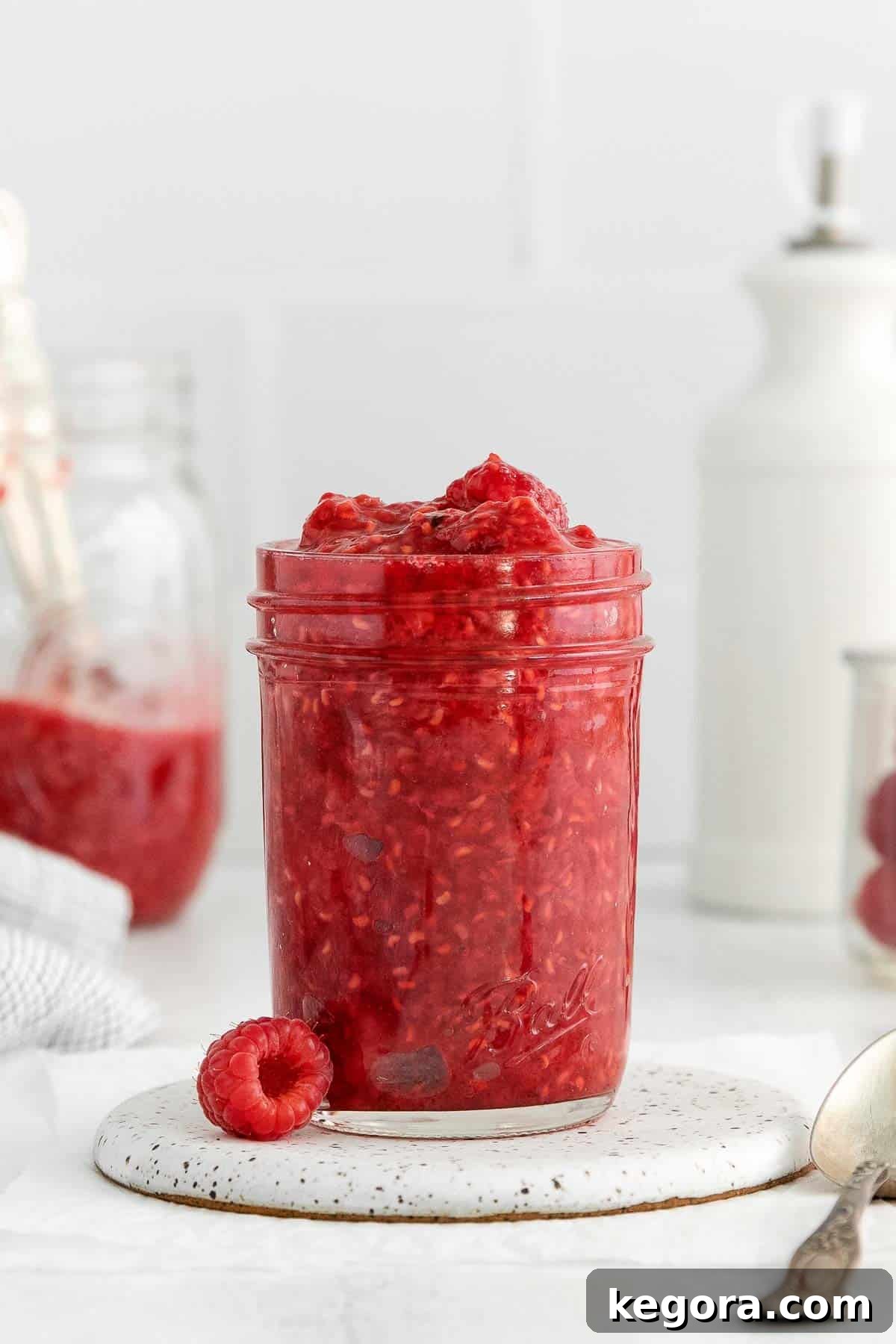Effortless Raspberry Delight 3 Vibrant raspberry compote elegantly displayed in a mason jar on a rustic countertop, showcasing its rich color and inviting texture.