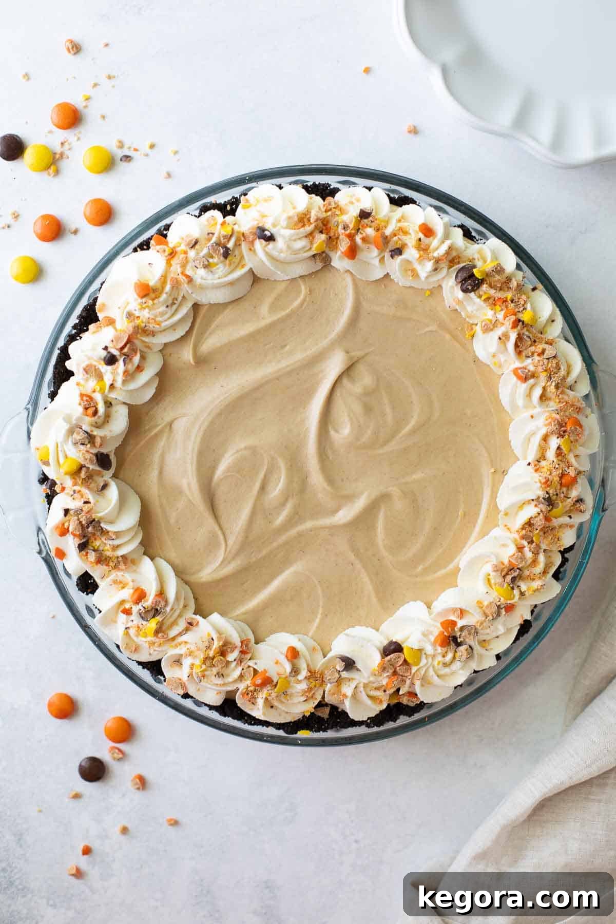 A delectable overhead view of a gluten-free peanut butter pie, adorned with frosting and peanut M&M candies, ready to be enjoyed.